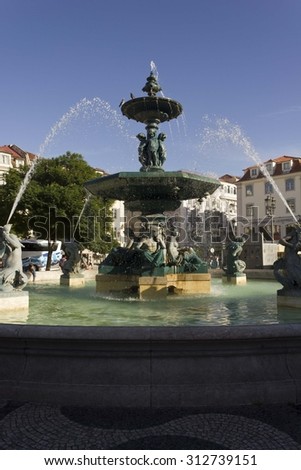 LISBON, PORTUGAL - OCTOBER 23 2014: Monumental fountain in Rossio Square in Lisbon, with few people around and a bus in the background