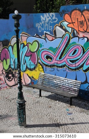LISBON, PORTUGAL - OCTOBER 26 2014: A bench in calcada do Lavra street in Lisbon, with no people and beautiful urban graffiti on the wall