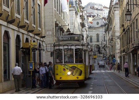 LISBON, PORTUGAL _ OCTOBER 24 2014: Rua Conceicao street in Lisbon with a series of tram and people walking, with Magdalene church in the background