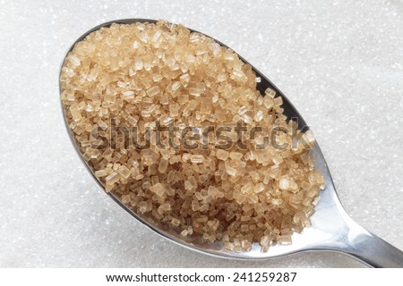 Brown sugar on spoon and white sugar in background