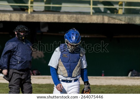 ZAGREB, CROATIA - MARCH 21, 2015: Baseball match Baseball Club Zagreb in blue jersey and Baseball Club Olimpija in gray jersey. Disappointed baseball catcher with bowed head leaving the field