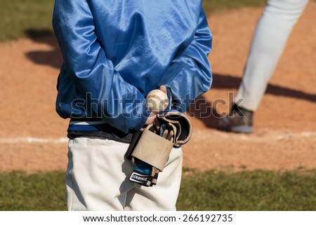 ZAGREB, CROATIA - MARCH 21, 2015: Baseball match Baseball Club Zagreb in blue jersey and Baseball Club Olimpija in gray jersey. Unidentified baseball player holding ball and gloves in hands