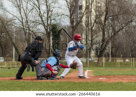 ZAGREB, CROATIA - MARCH 28, 2015: Baseball match Baseball Club Zagreb in white jersey and Baseball Club Nada in blue jersey. Baseball batter, catcher and plate umpire.