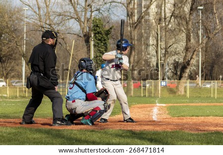 ZAGREB, CROATIA - MARCH 28, 2015: Baseball match Baseball Club Zagreb in white jersey and Baseball Club Nada in blue jersey. Baseball batter, catcher and plate umpire