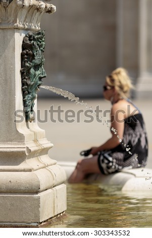 ZAGREB, CROATIA - AUGUST 05, 2015: Water fountain in Zagreb, woman tourist cooling down and resting her feet in the fountain