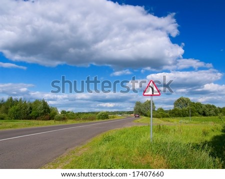 Road in countryside with dangerous turn left sign