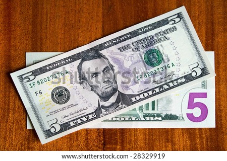 Five-dollar bills on a wooden table
