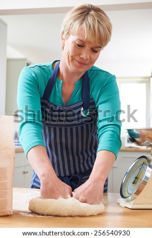 Woman Wearing Apron Kneading Dough In Kitchen