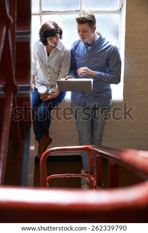 Two Businesspeople Having Informal Meeting On Office Stairs