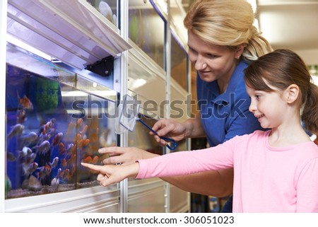 Girl With Sales Assistant Choosing Goldfish In Pet Store
