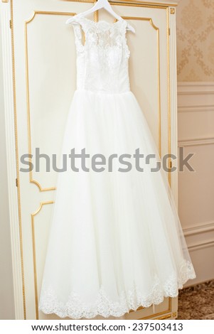 White Wedding dress hanging on a shoulders. Soft light and colours