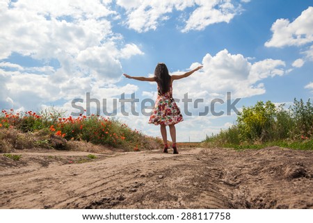 The beautiful young girl onon the road in  the poppy field. Freedom