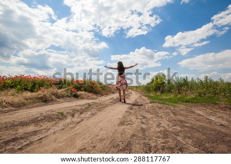 The beautiful young girl onon the road in  the poppy field. Freedom