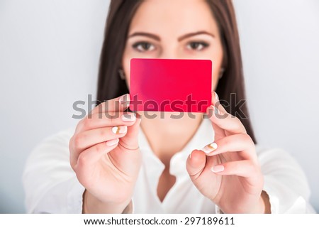 Close-up portrait of young pretty business woman holding red credit card.  focus on the credit card