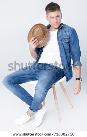 handsome man in denim with hat sits on chair on white background Stok fotoğraf © 