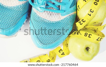 Sport shoes, green apple and a measuring tape. Fitness concept
