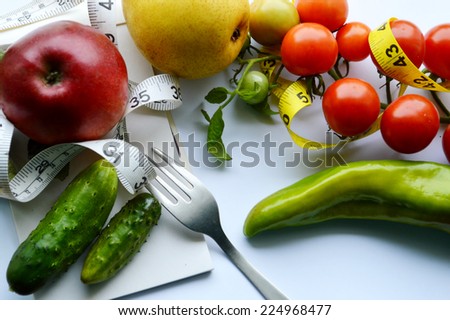 vegetables and fruits for weight loss, a measuring tape, diet, weight loss. red Apple , cucumber,peppers,tomatoes ,yellow pear,Notepad, fork