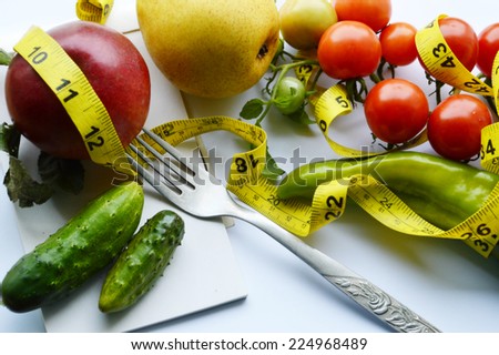 vegetables and fruits for weight loss, a measuring tape, diet, weight loss red Apple , cucumber,peppers,tomatoes ,yellow pear,Notepad, fork