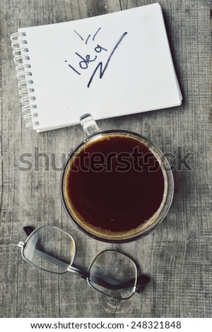 Notepad,reading glasses,hot Cup of coffee on wooden background