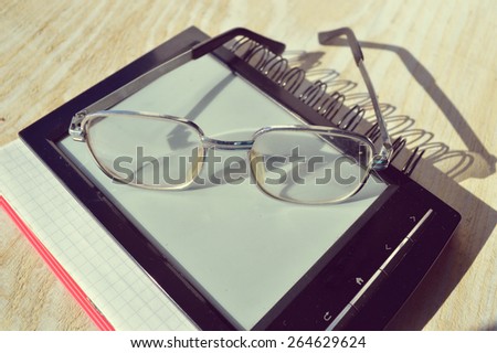 black e-book,reading glasses,Notepad,diary,reading glasses and magnifying glass on wooden table