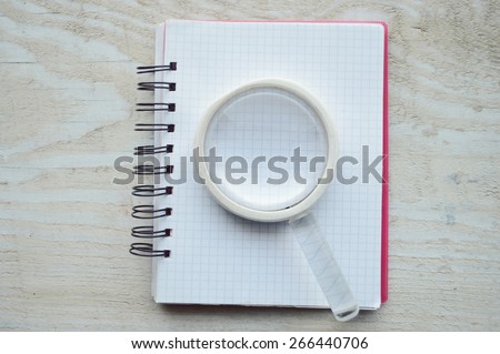 notebook, diary, glasses, pen, magnifying loupe close-up on a wooden table
