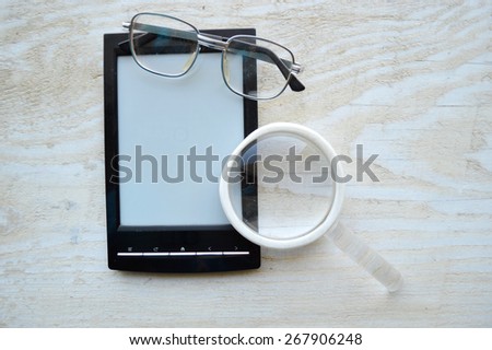 black e-book,reading glasses,Notepad,diary,reading glasses and magnifying glass on wooden table