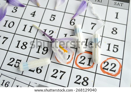 Woman hygiene protection, close-up.menstruation calendar with cotton tampons,orange Gerber,Sanitary pads.Spring flowers, femininity, tenderness, birth control pills