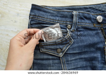 condom in blue jeans pocket,Protect yourself Use a condom.a woman holding a condom ,ready for use