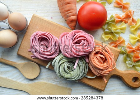 still life with raw homemade pasta and ingredients for pasta.process of cooking pasta.natural dyes for pasta (tomato, spinach, carrots)