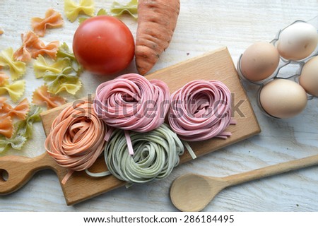 still life with raw homemade pasta and ingredients for pasta.process of cooking pasta.natural dyes for pasta (tomato, spinach, carrots)