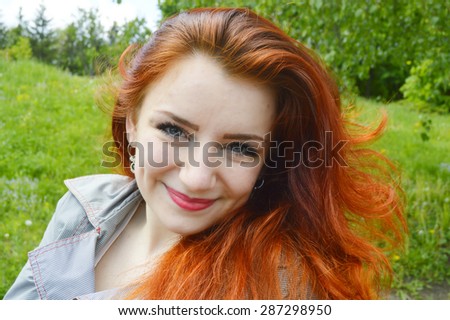 Beautiful young redhead woman smiling with closed eyes, enjoying nature, relaxing, meditating.beautiful hair fluttering in the wind