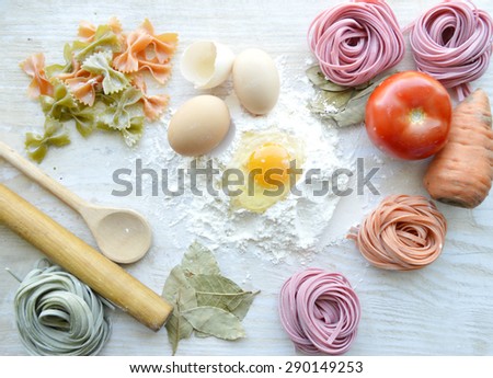 still life with raw homemade pasta and ingredients for pasta.process of cooking pasta.natural dyes for pasta (tomato, spinach, carrots),ingredients for homemade pasta(flour, eggs, water)