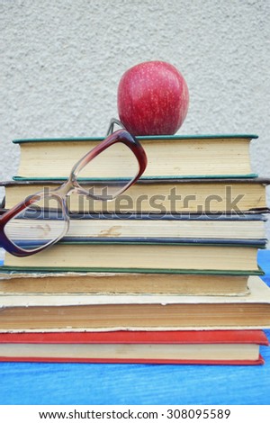 Back to school concept.autumn.Apple on old books,magnifier ,reading glasses on wooden background
