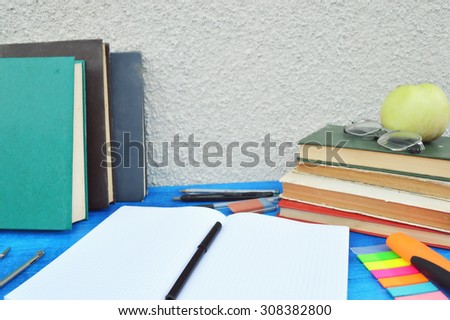 Books, apple, notebook,reading glasses, pencils on wood desk table and black board. Back to school concept.autumn