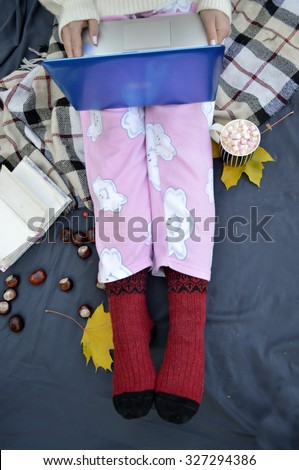 Soft photo of woman on the bed with notebook,  cup of coffee, top view point.Female legs in warm woolen socks