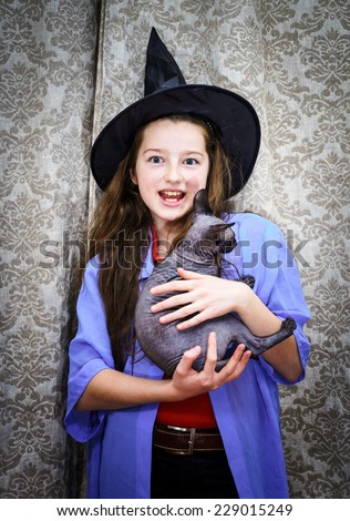 Teenage girl dressed in witch costume with sphynx cat