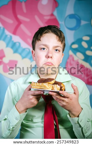 Funny teenage boy eating sweet cakes, hungry and candy man