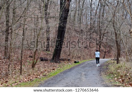 A girl walking on a dirt path in the woods in Fick Park located in Pittsburgh, Pennsylvania, USA in winter time with bare trees Stock fotó © 