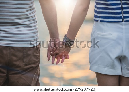 Concept shoot of friendship and love of man and woman: two hands over sun ray and nature