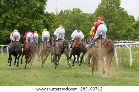 STOCKHOLM - JUNE 06: Rear view of a group of race horses and jockeys before a curve at the Nationaldags Galoppen at Gardet. June 6, 2015 in Stockholm
