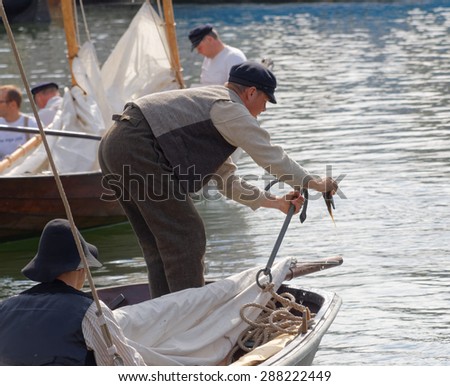 GRISSLEHAMN - JUN 13, 2015: Sailor in vintage clothes fixing the anchor before the public event Postrodden, June 13, 2015 in Grisslehamn, Sweden