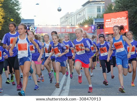 STOCKHOLM, SWEDEN - AUG 15, 2015: Group of 12 year old girls in blue dresses running in the running event Midnattsloppet, August 15, 2015 in Stockholm, Sweden