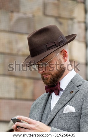 STOCKHOLM - SEPT 19, 2015: Man wearing hat and tweed looking at his phone in the Bike in Tweed event September 19, 2015 in Stockholm, Sweden