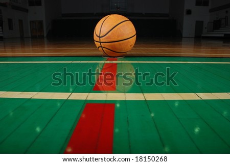 A gymnasium\'s shiny floor and leather basketball.