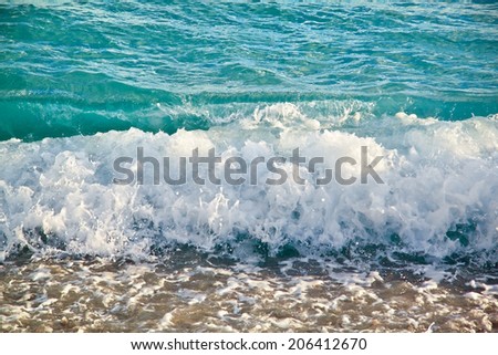 Azure sea waves. Clear blue water with white foam. Pebbles on the beach. Nice, France. Summer in Europe.