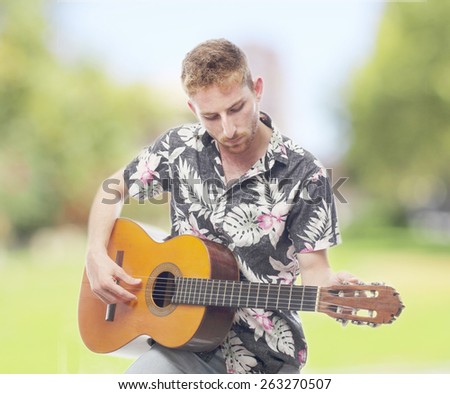 ginger young man with hawaiian shirt playing the guitar