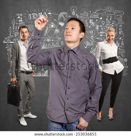 Teamwork concept. Business team and man writing something on glass board with marker