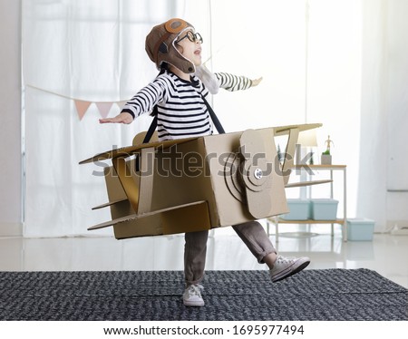 Asian little child girl playing with cardboard toy airplane handicraft isolated in home with copy space for your text, Creative with family and dreaming of flying concept