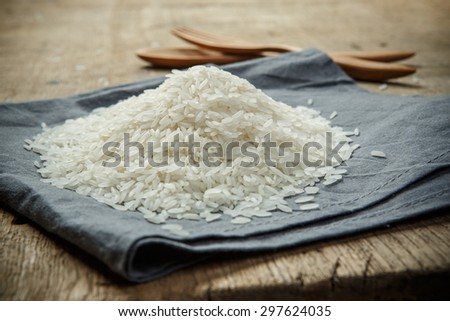 Uncooked rice grains on the fabric with wooden spoon and folk - soft focus