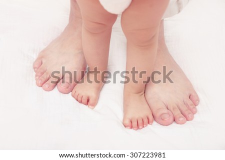 First steps. Baby learning to walk, with help of mothers and fathers. (Soft focus and blurry)